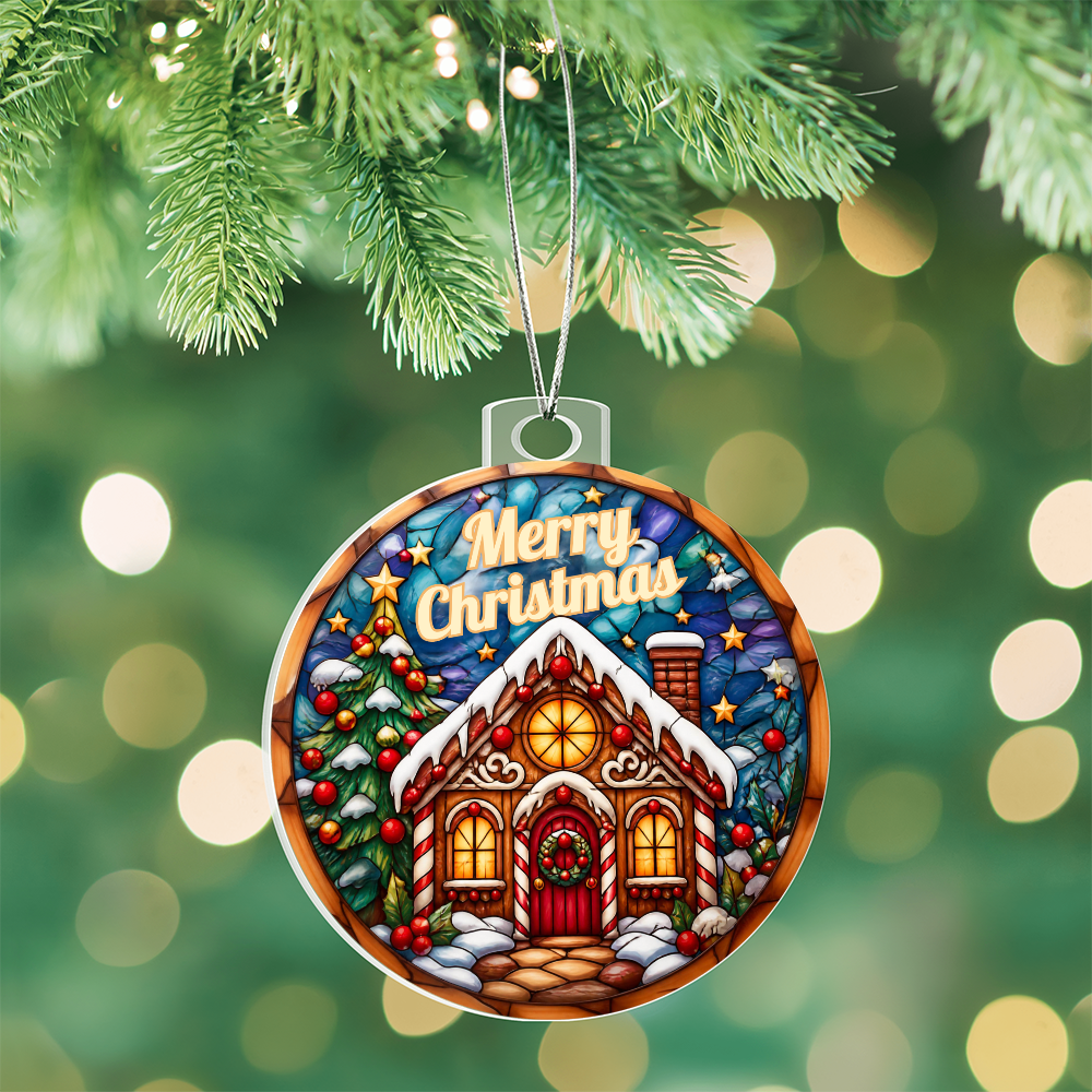 Round acrylic Christmas ornament in a stained-glass style featuring a cozy gingerbread house with "Merry Christmas" written at the top, hanging from pine branches on a Christmas tree with soft bokeh lights in the background.