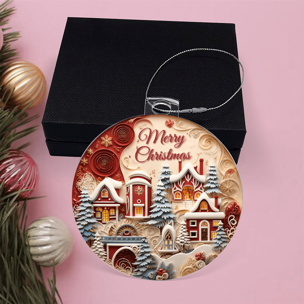 Round acrylic Merry Christmas winter village ornament leaning against a black gift box with silver hanging cord .