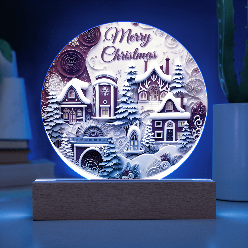Winter House round acrylic desk plaque glowing with blue LED backlighting, featuring a snow-covered village and Merry Christmas text on a wooden base.