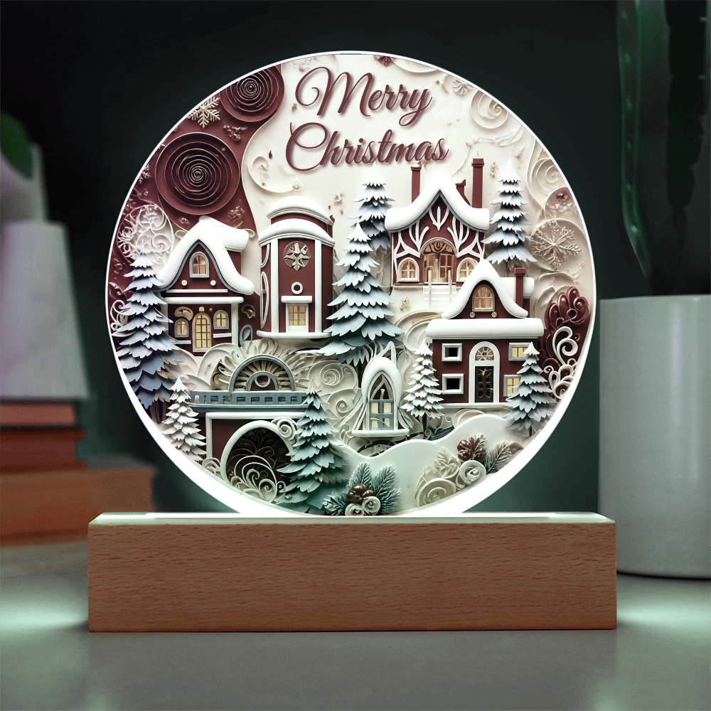 Winter House round acrylic desk plaque glowing with green LED backlighting, featuring a snow-covered village and Merry Christmas text on a wooden base.